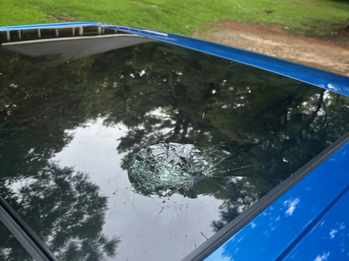 Blue sedan with damaged sunroof glass before replacement
