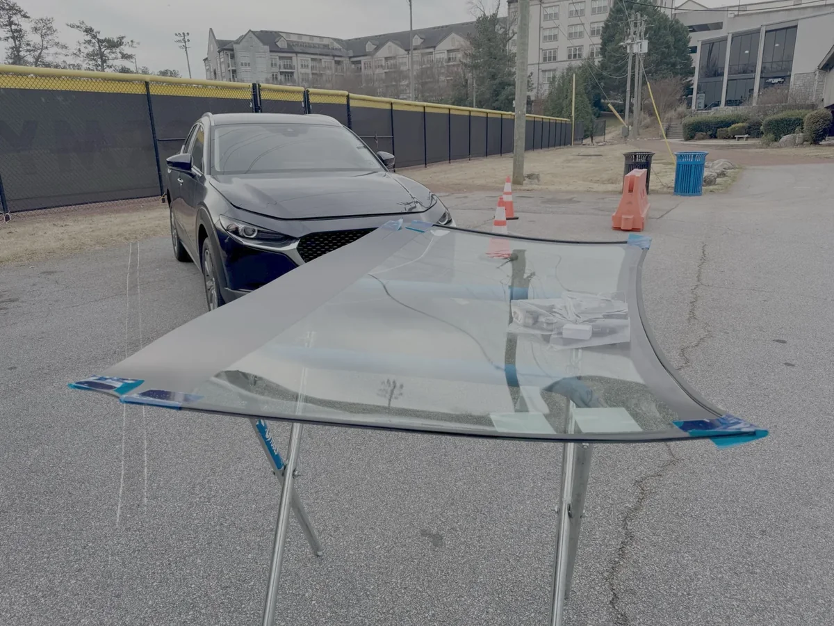 Mazda replacement windshield staged on a padded stand before installation