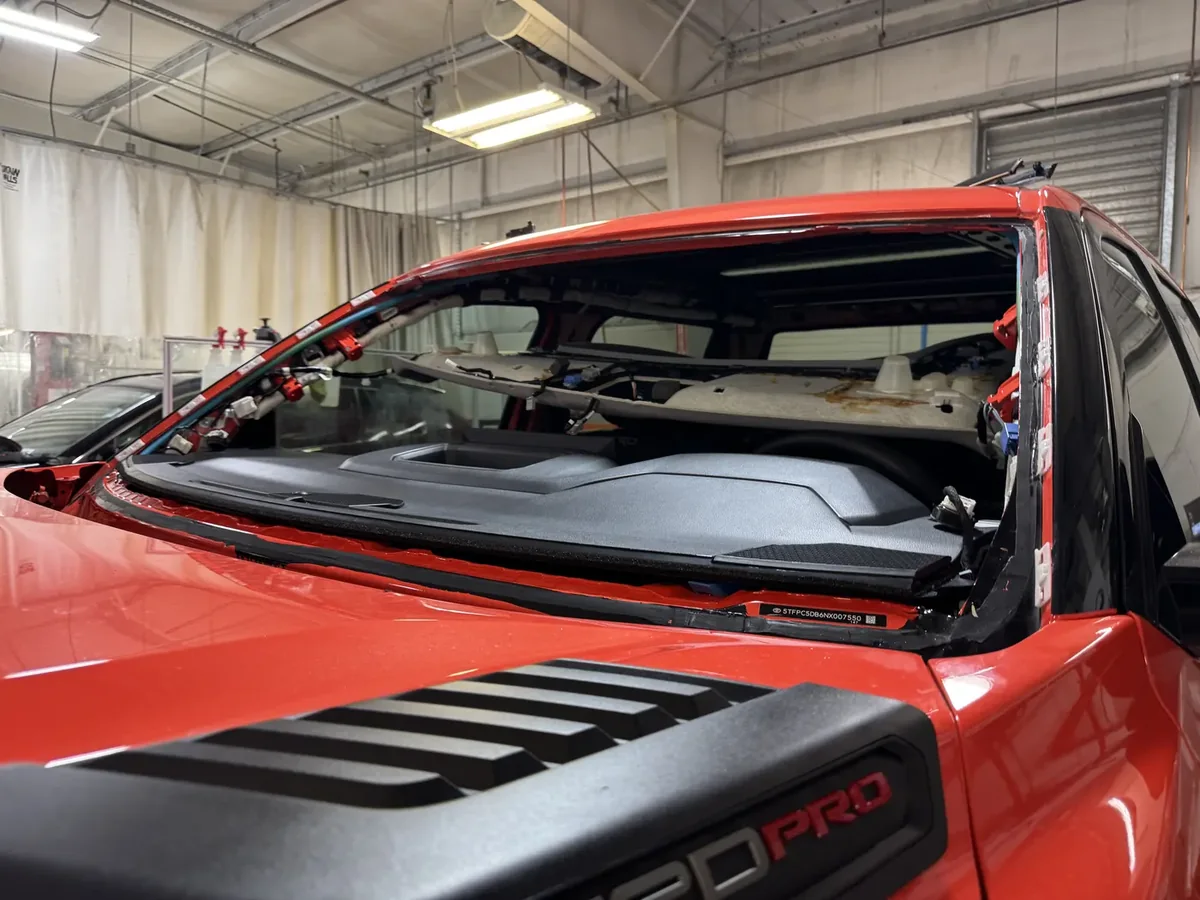 Windshield replacement in progress on a red vehicle