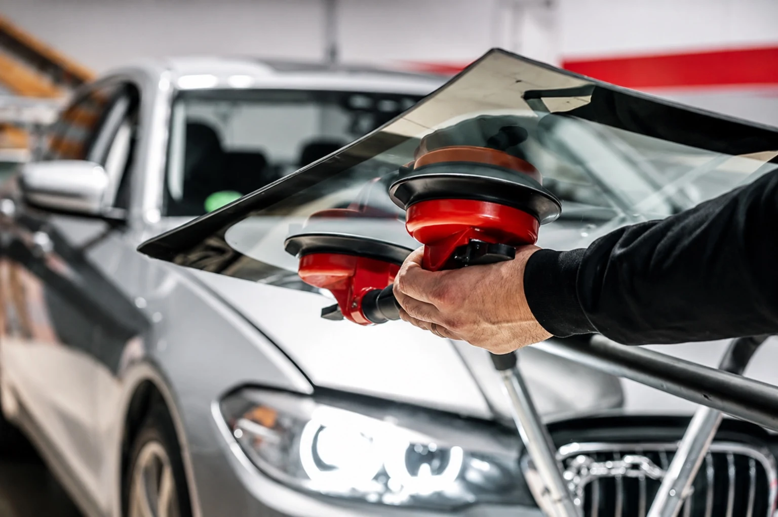 Auto glass technician carrying replacement glass with professional lifting tools
