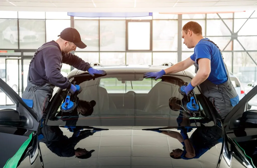 Technicians setting a windshield into place to confirm the right auto glass service