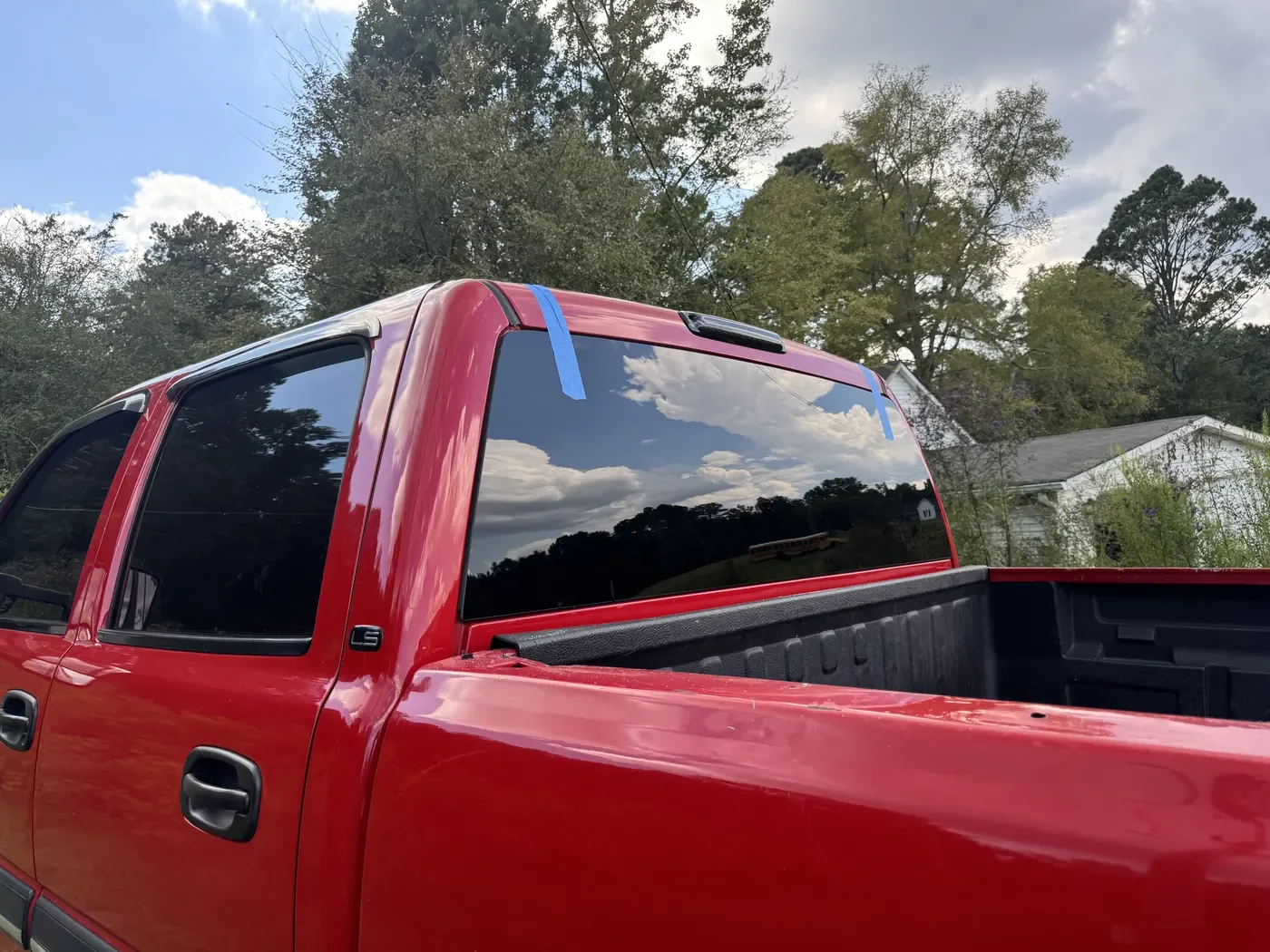 Freshly installed rear back glass on a red pickup truck