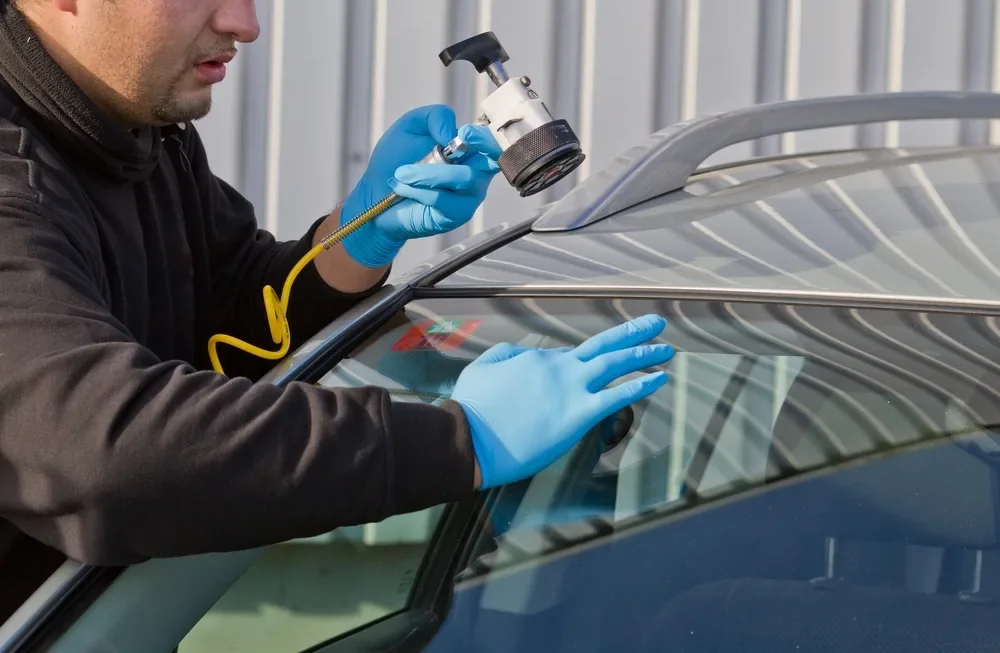 Technician using a repair tool on a vehicle windshield
