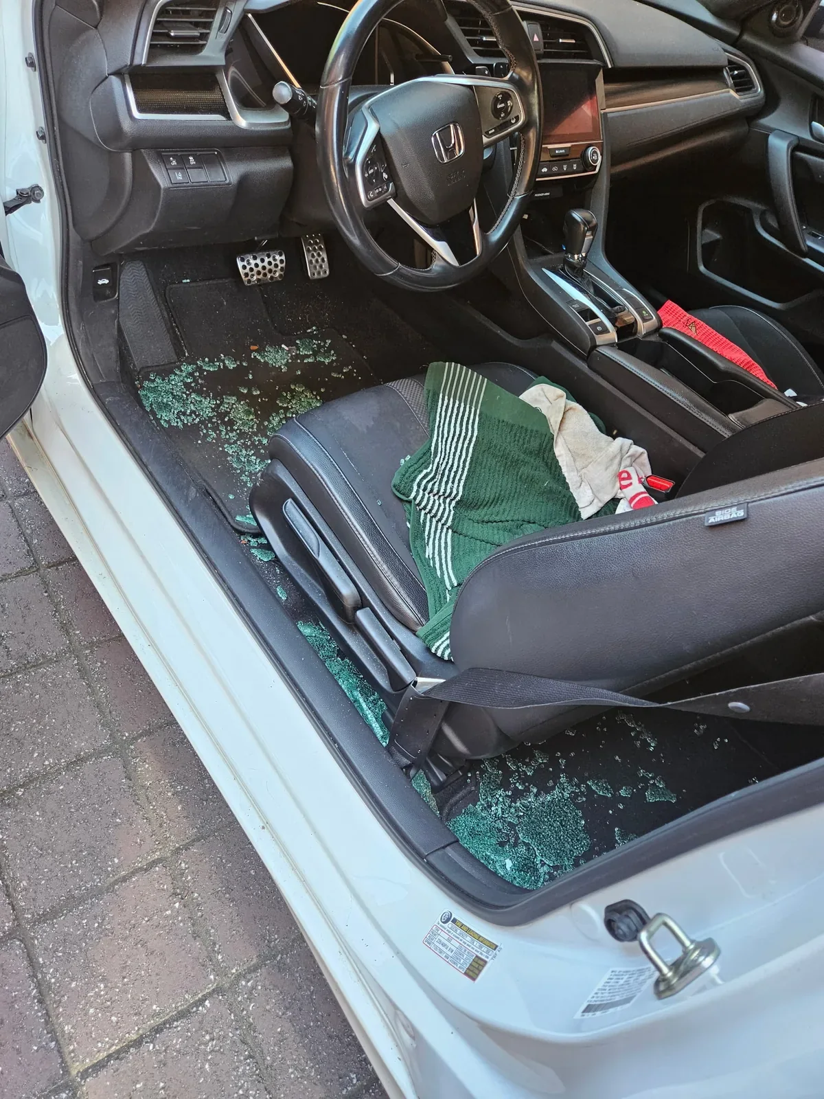 Broken side door glass scattered inside a vehicle before cleanup and replacement