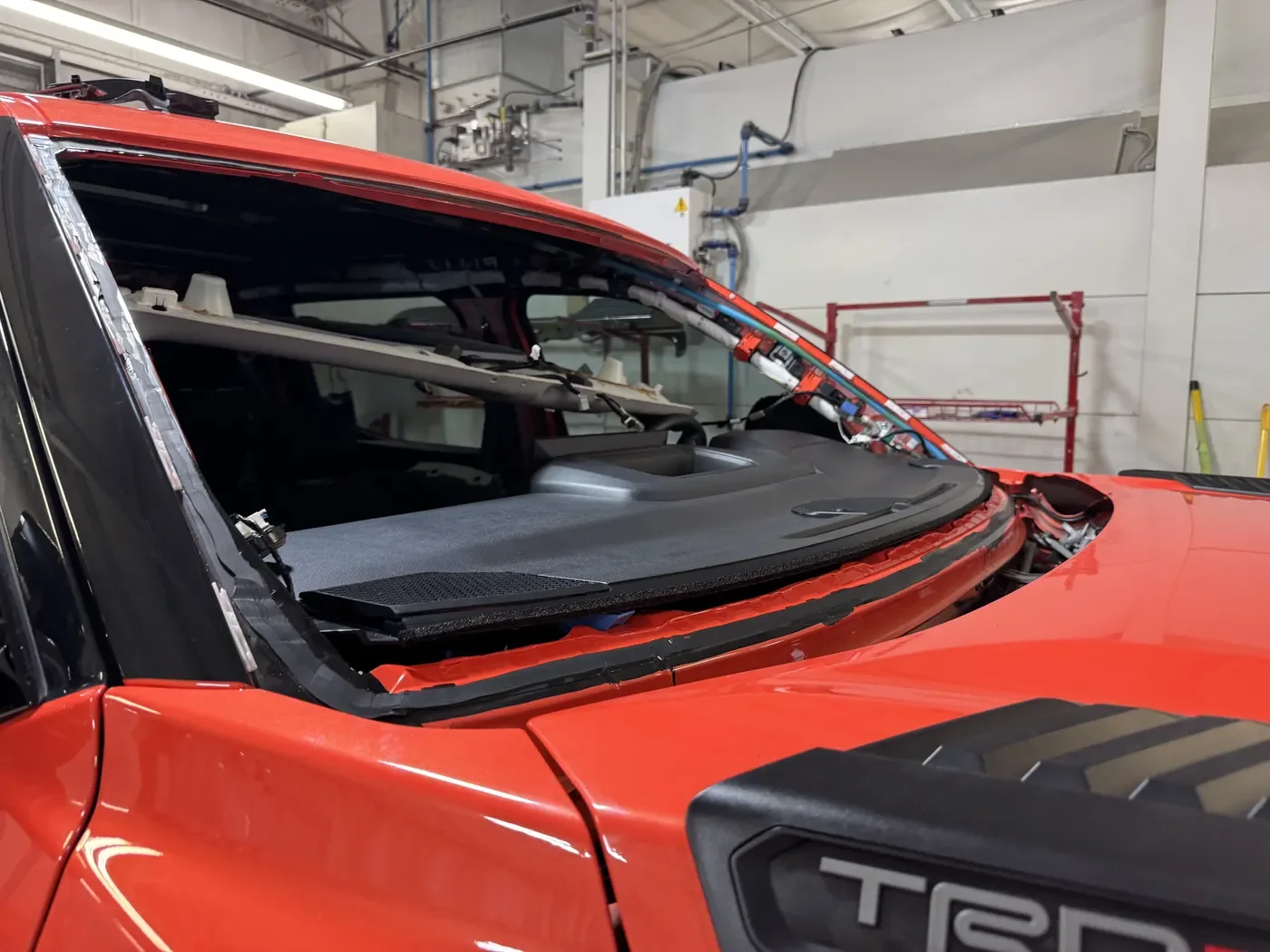 Red truck windshield removed and prepared for replacement in an auto glass shop